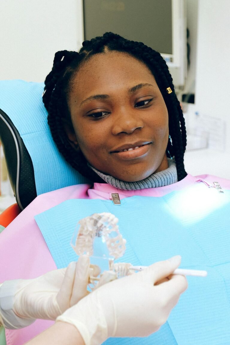A black woman smiles during a dental checkup, showcasing dental care.
